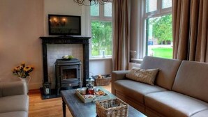 Una sala de estar acogedora con chimenea, un sofá, una mesa de centro y un televisor sobre la chimenea.