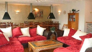A cozy living room with a red velvet sofa set, wooden coffee table, and pendant lighting.