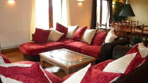 A living room with a red sofa set, a coffee table, and a dining area with chairs.