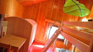 Een houten hut met stapelbedden, een bureau en een groene paraplu.