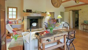 A rustic interior with exposed wooden beams, a fireplace, a dining table with chairs, and a bookshelf. - Hilltop Home with Valley View (Bouzic)
