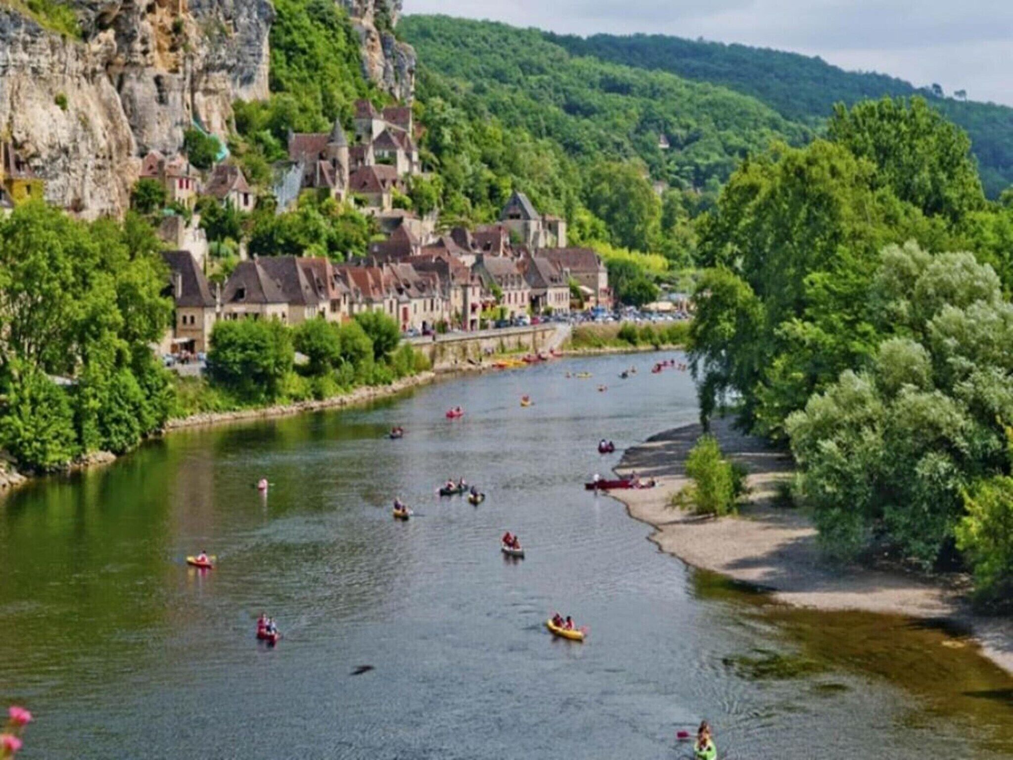 Un río con barcos, rodeado de exuberante vegetación y edificios históricos.