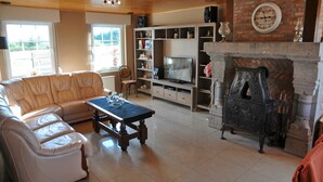 Un saló amb un sofà, una taula de centre, una llar de foc, una televisió i prestatges amb objectes decoratius.