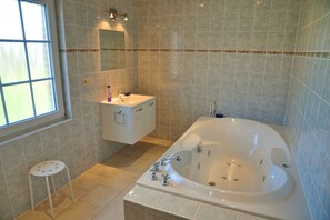Une salle de bain avec une baignoire, un lavabo, un miroir et une fenêtre.