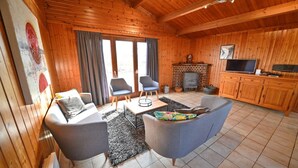 Ein gemütliches Blockhaus-Interieur mit Kamin, Fernseher und Essbereich.