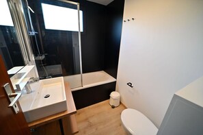 Een moderne badkamer met een wit wastafel, een bad en een toilet.