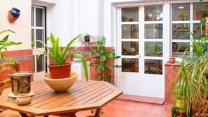 Une terrasse avec une table en bois, des plantes en pot et un sol carrelé.