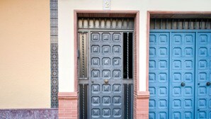 Une façade d’immeuble avec deux portes, une noire et une bleue, et le chiffre « 2 » au-dessus de la porte noire.