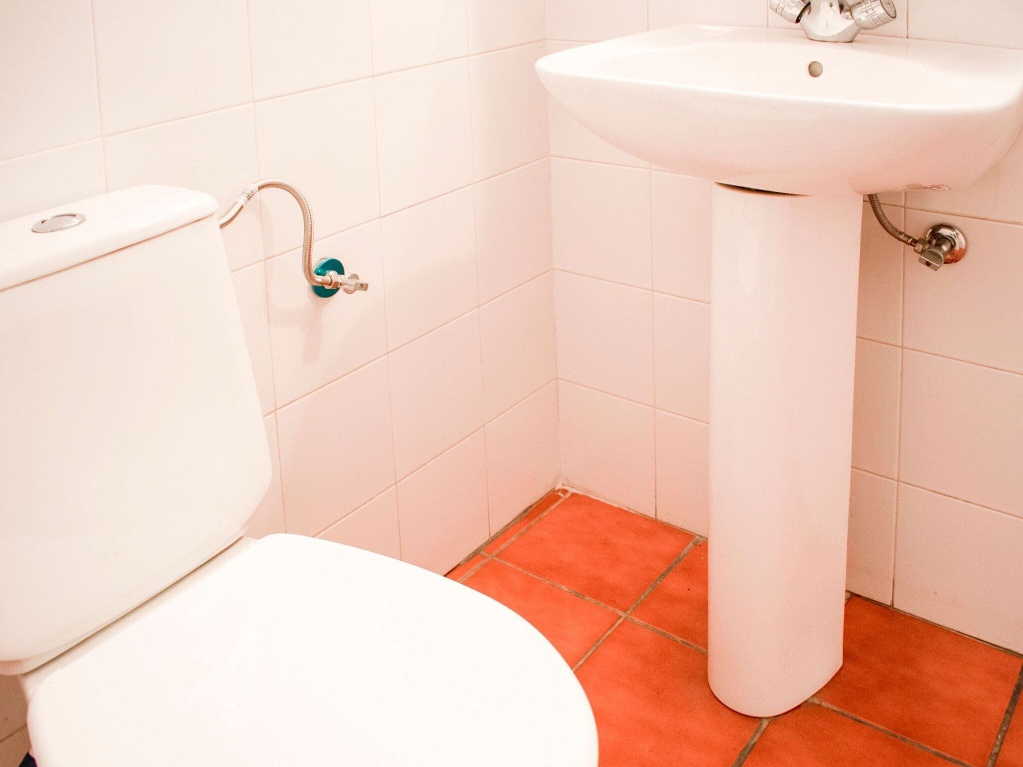 Ein Badezimmer mit Toilette, Waschbecken und roten Fliesen.