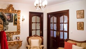 Une pièce avec un grand miroir, un lustre, une porte en bois et un canapé.