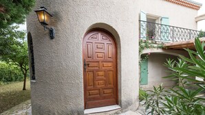 Un edificio de piedra con puerta de madera, una escalera de piedra y un balcón con barandilla de metal.