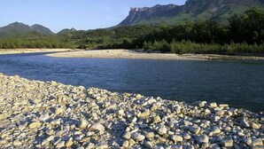 Une rive rocheuse, d’où l’on a une vue dégagée sur les montagnes à l’arrière-plan.