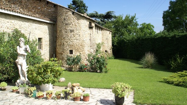 Un bâtiment en pierre avec une statue dans le jardin.