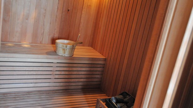 Un sauna en bois avec un banc et un récipient.
