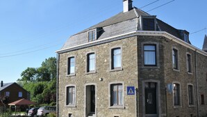 Un bâtiment en pierre doté de nombreuses fenêtres et d’une porte, sur lequel on peut voir un panneau indiquant un passage piéton.