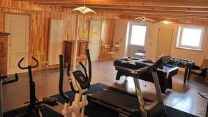Une salle de sport équipée de matériel d’exercice, notamment des tapis de course et une table de baby-foot.