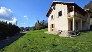 Una casa a due piani con una scala in pietra che conduce a un portico in legno.