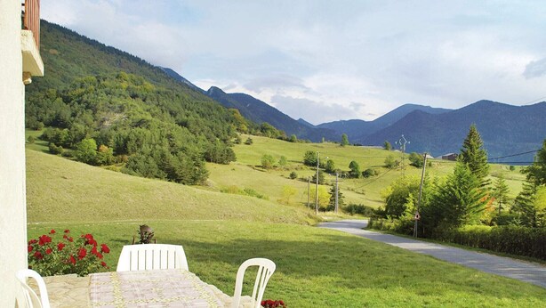 Un tavolo con sedie su un patio con vista su un paesaggio montuoso.