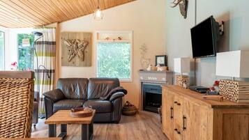 Ein gemütliches Wohnzimmer mit einer Ledersofa, einem Holztisch, einem Kamin und einem an der Wand befestigten Fernseher.