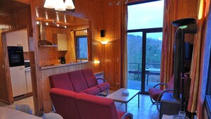 Een knus interieur van een chalet, met een eethoek, een bank en een tafel met een decoratieve vaas.