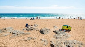 Ein Strand mit Personen, einem Zelt und Felsen.