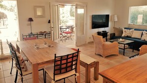 Un grand espace de vie comprenant une table à manger, des chaises, un canapé et un téléviseur.