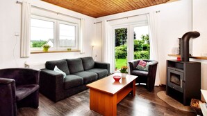 A cozy living room with a wooden ceiling, a sofa set, a coffee table, and a fireplace. - Wellness Escape in Gouvy (Gouvy)