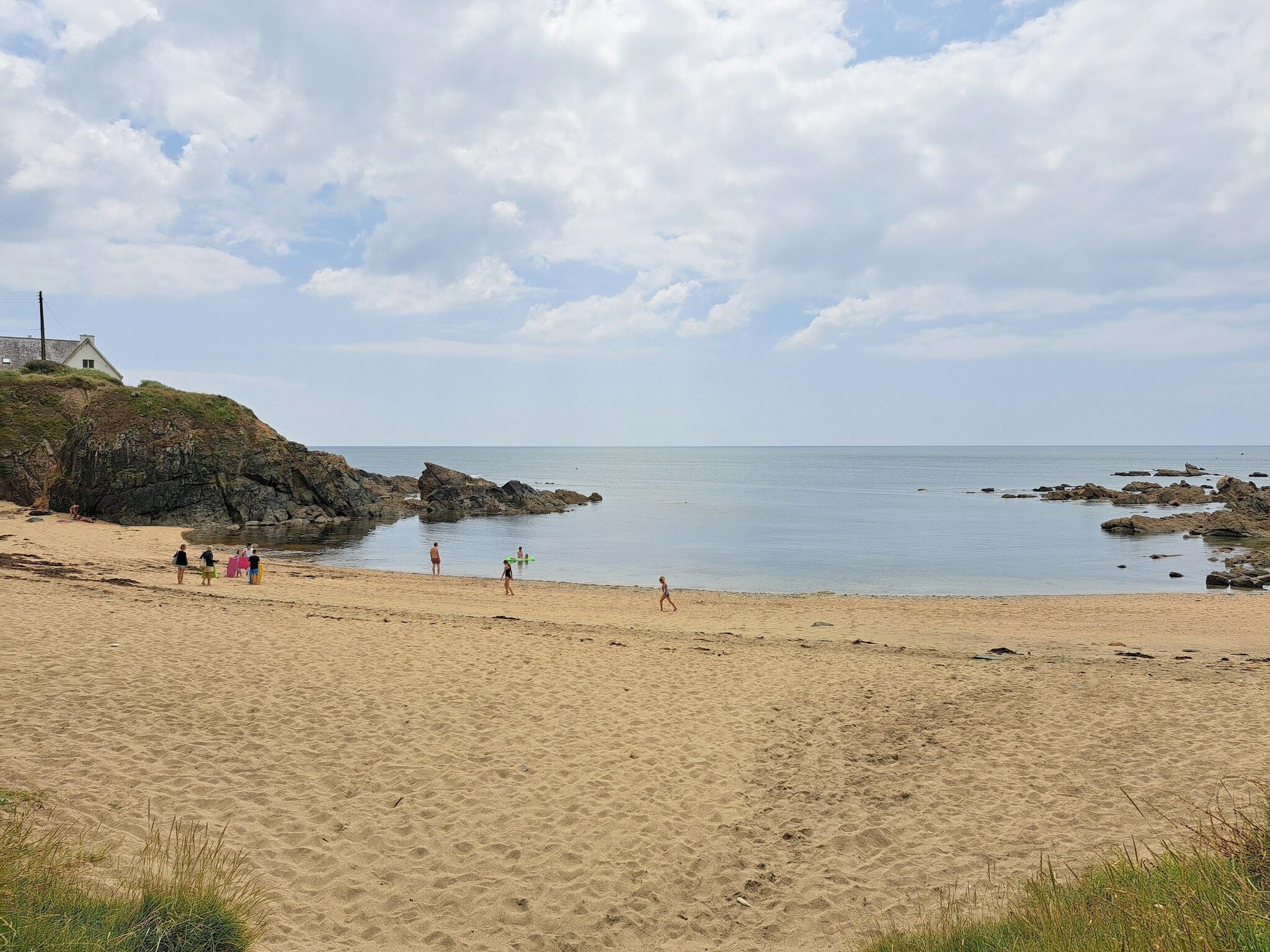 A sandy beach with rocky outcrops and a clear sky.