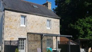 Un bâtiment en pierre doté d’un patio couvert, d’une petite fenêtre et d’une porte.