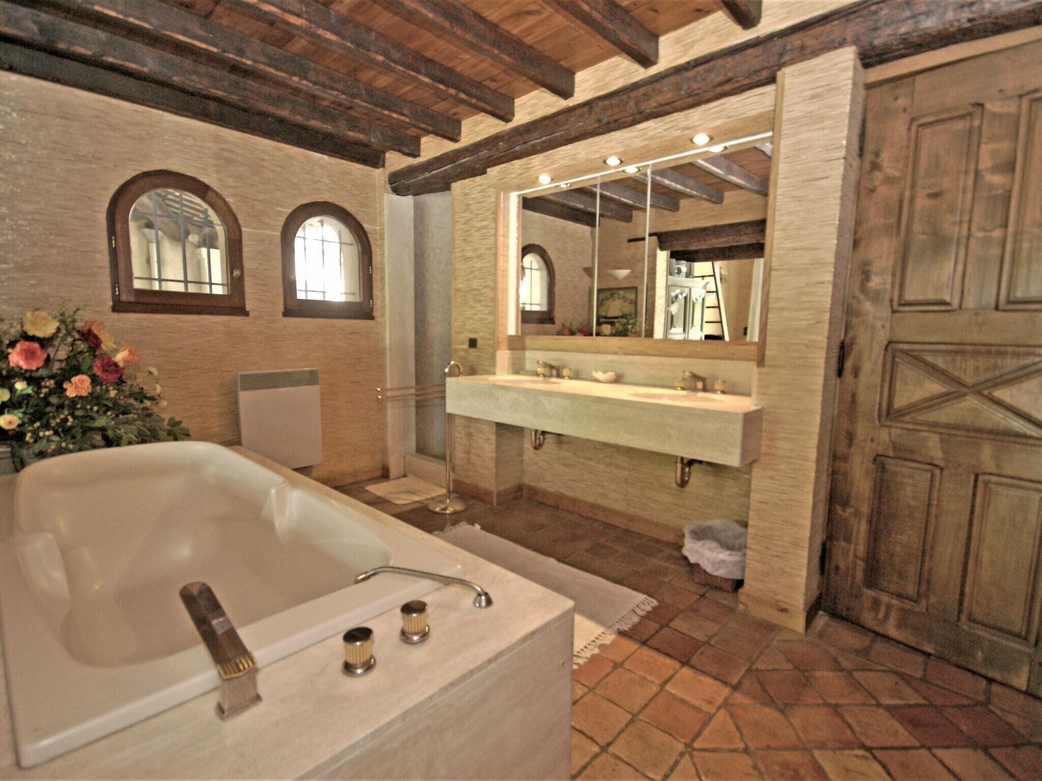 A bathroom with a large bathtub, a double sink vanity, and a wooden door.