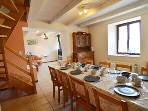 A dining area with a table set for four, wooden chairs, a wooden cabinet, and a window with curtains. - Modern Farmhouse in Chassepierre with Terrace (Chassepierre)