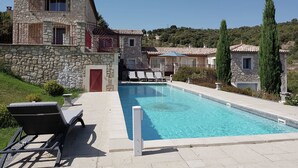 A stone villa with a swimming pool, outdoor seating, and a view of the surrounding landscape. - Cosy holiday home with views and private pool (Saint-Ambroix)