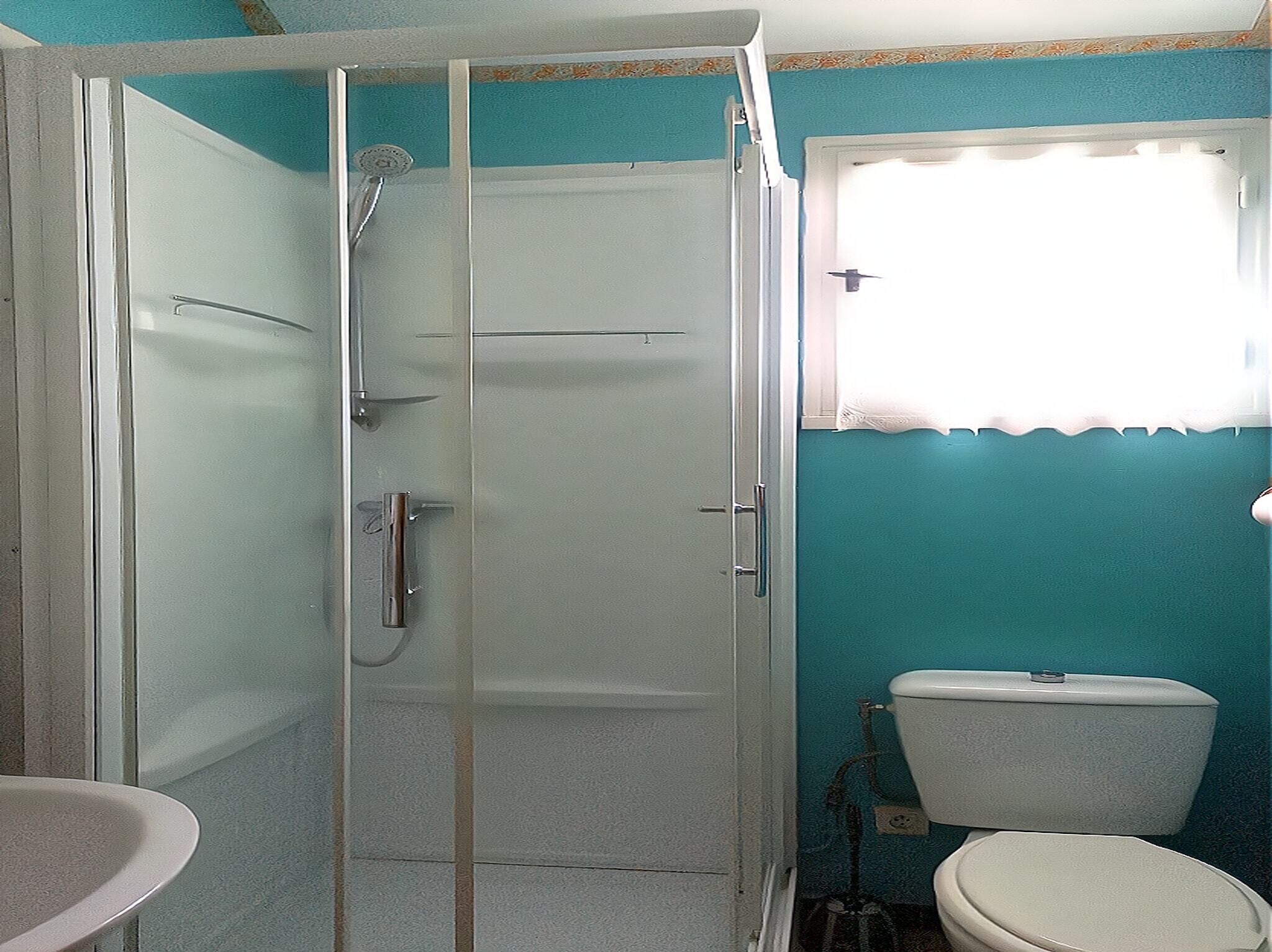 Une salle de bain avec une douche à parois de verre, des toilettes et un lavabo.