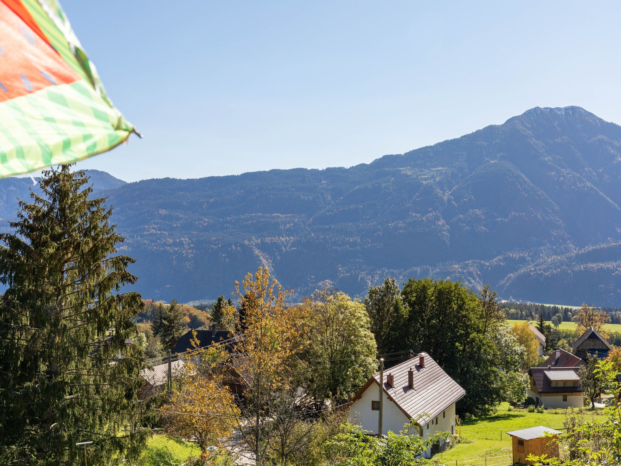 Un paysage rural avec des maisons, une montagne et un ciel dégagé.