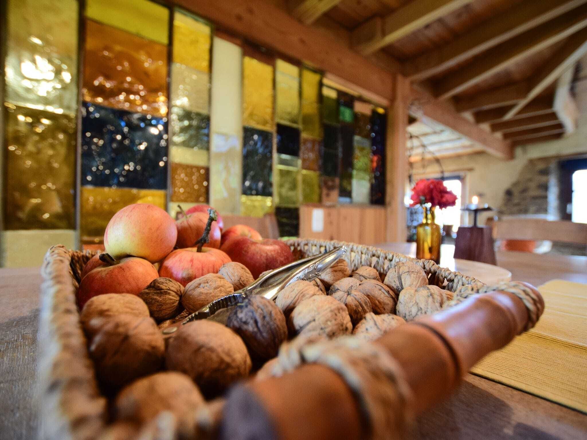 Ein Korankorb gefüllt mit Äpfeln, Walnüssen und einem Eiszange auf einem Holztisch.