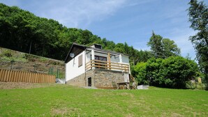 Une petite maison de plain-pied, avec des fondations en pierre et un balcon en bois.