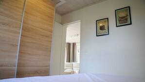 Une chambre d’hôtel avec une tête de lit en bois, un lit recouvert de draps blancs et deux citations encadrées accrochées au mur.