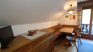 Une petite cuisine avec un comptoir en bois, un évier et un coin repas comprenant une table et des chaises.