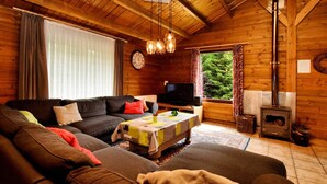 Acogedor interior de cabaña de madera con sofá, televisor y chimenea.