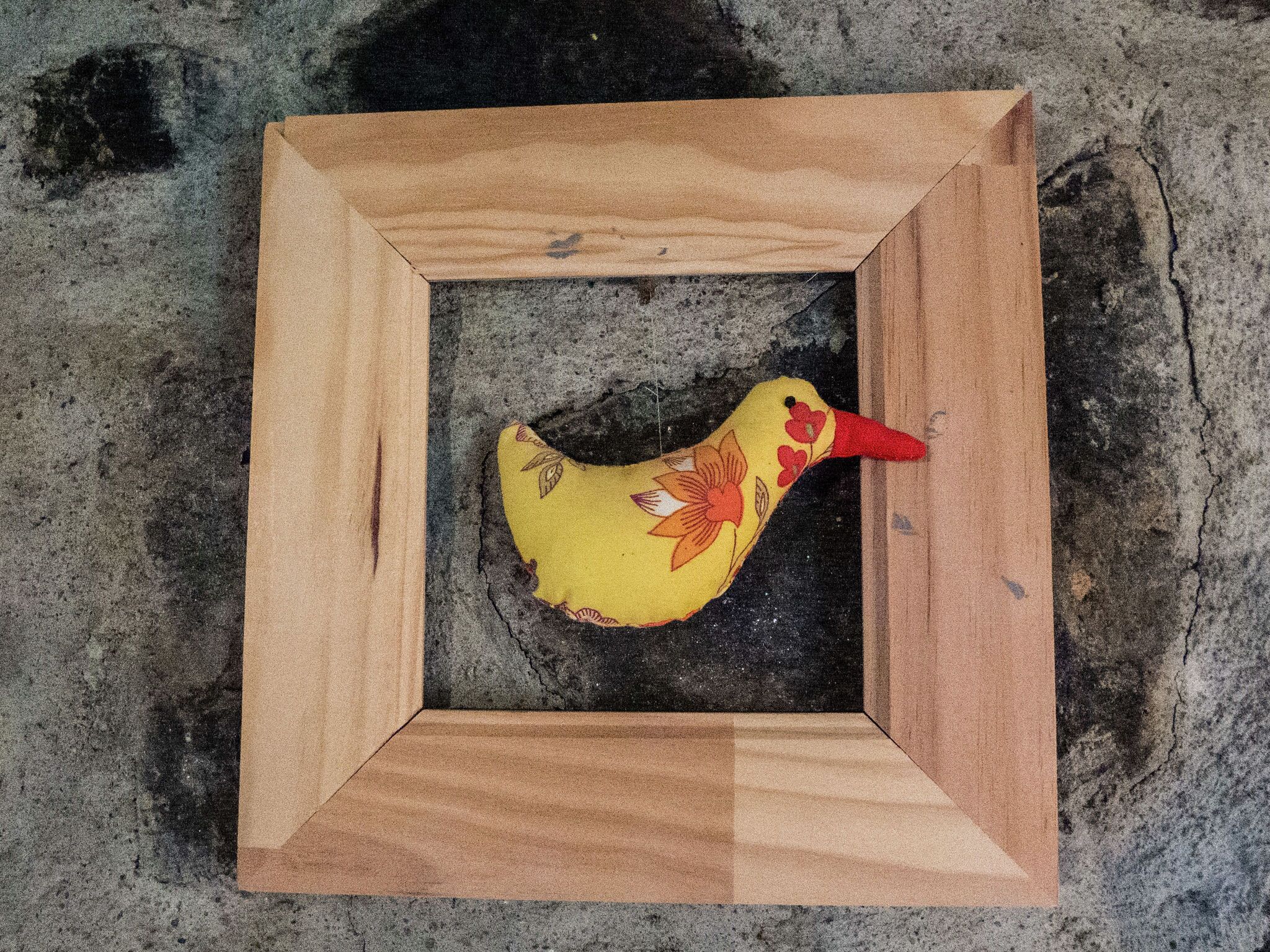A wooden frame with a yellow bird decoration inside.