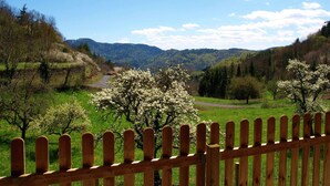 Una cerca de madera con vista a un valle y montañas al fondo.