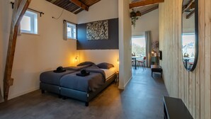 A bedroom with a bed, bedside lamps, a window, and a view of the outside.