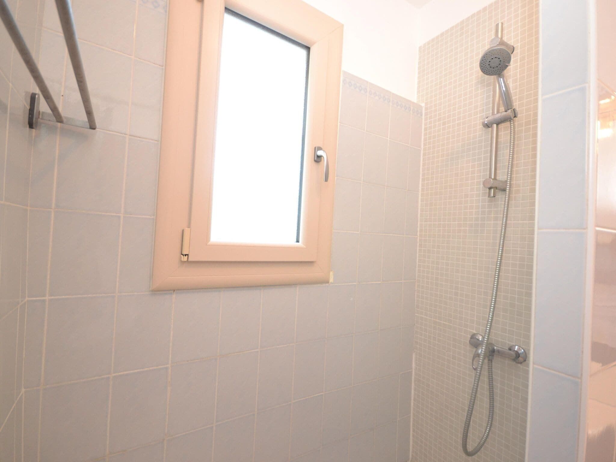 A shower with a handheld showerhead and a wall-mounted faucet.