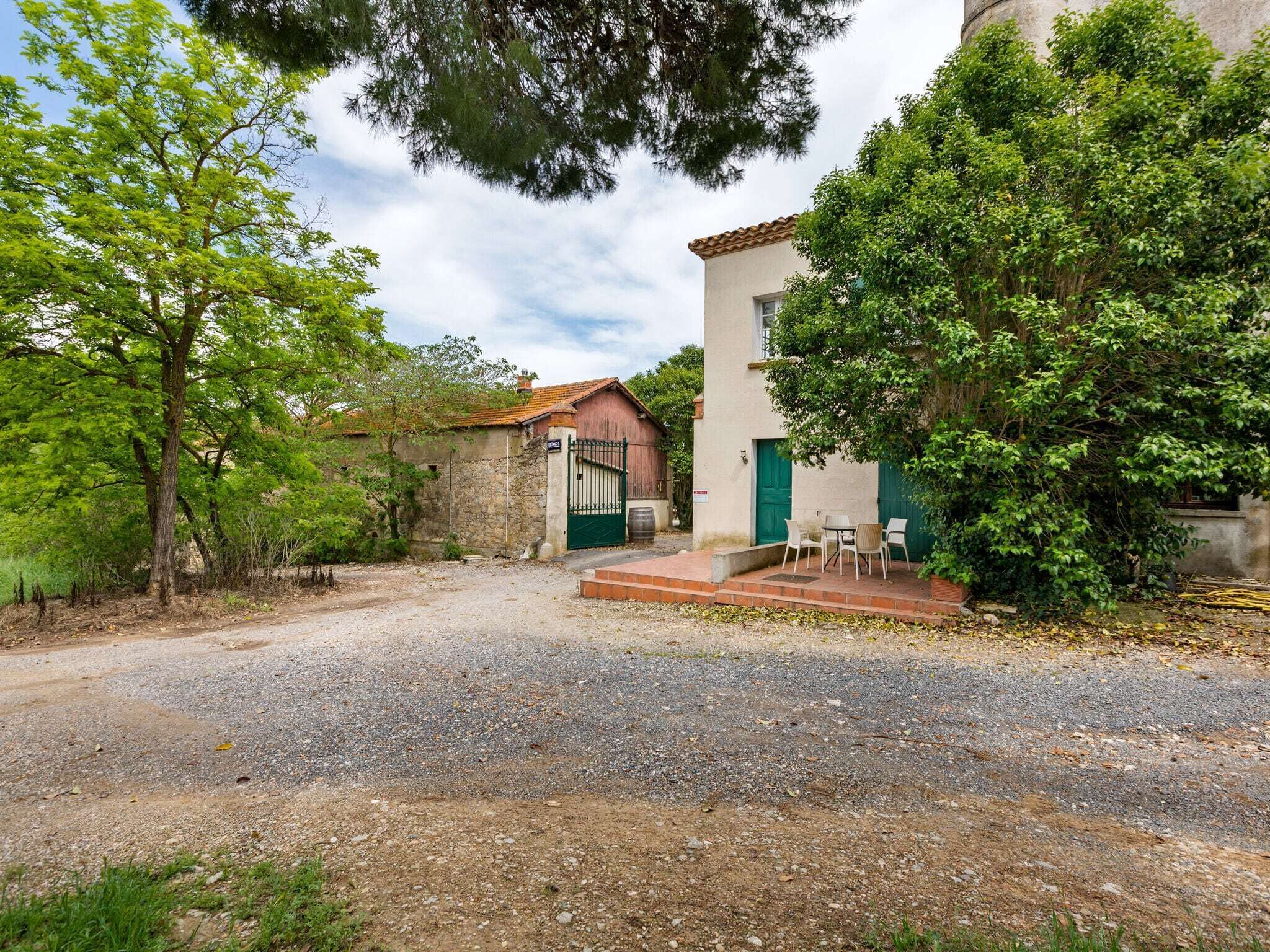 A rustic building with a gravel driveway, a green door, and a small patio with outdoor seating.