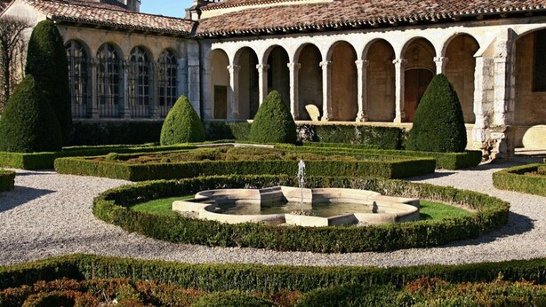 A courtyard with a fountain, surrounded by neatly trimmed hedges and a building with arched windows and a tiled roof. - Panoramic Poolside Villa (La Croix-Blanche)