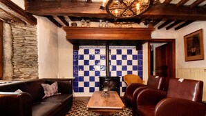 A cozy room with a checkered floor, a wooden table, leather sofas, and a stone wall.