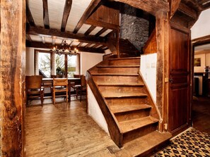 Una rústica escalera de madera conduce a un entrepiso con vigas a la vista y paredes de piedra.