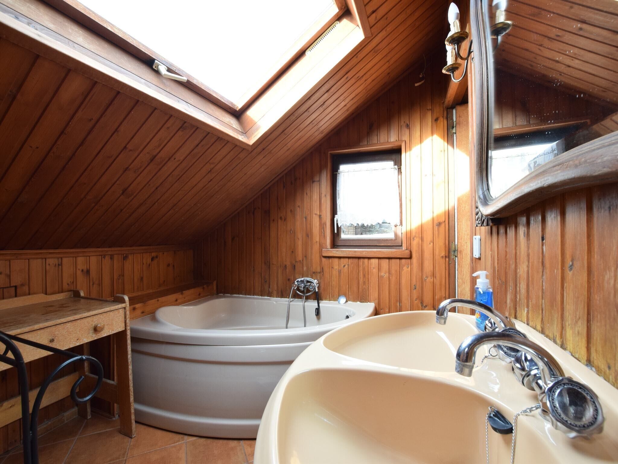 Ein Badezimmer einer Holzhütte mit Dachfenster, einer Badewanne, einem Waschbecken und einem Fenster.