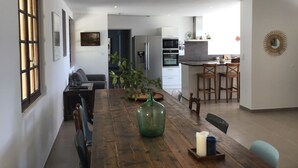 Une cuisine moderne avec un îlot central, un coin repas doté d’une table en bois et un salon avec un canapé et une table basse.