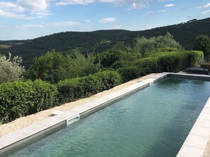 A rectangular swimming pool with clear water, surrounded by a pebble-lined edge and lush greenery. - Tranquil Vineyard Villa, Berlou (Berlou)